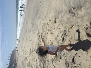 A young child walking along the shoreline on a field trip to the beach