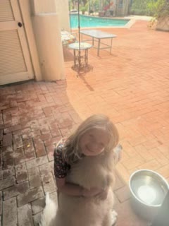 A child hugging a golden dog on a sunny patio