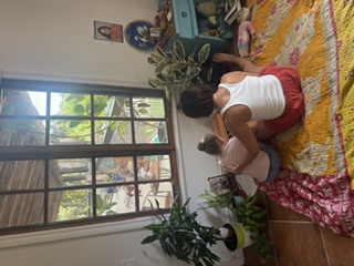 Two children sitting quietly by a garden window surrounded by plants