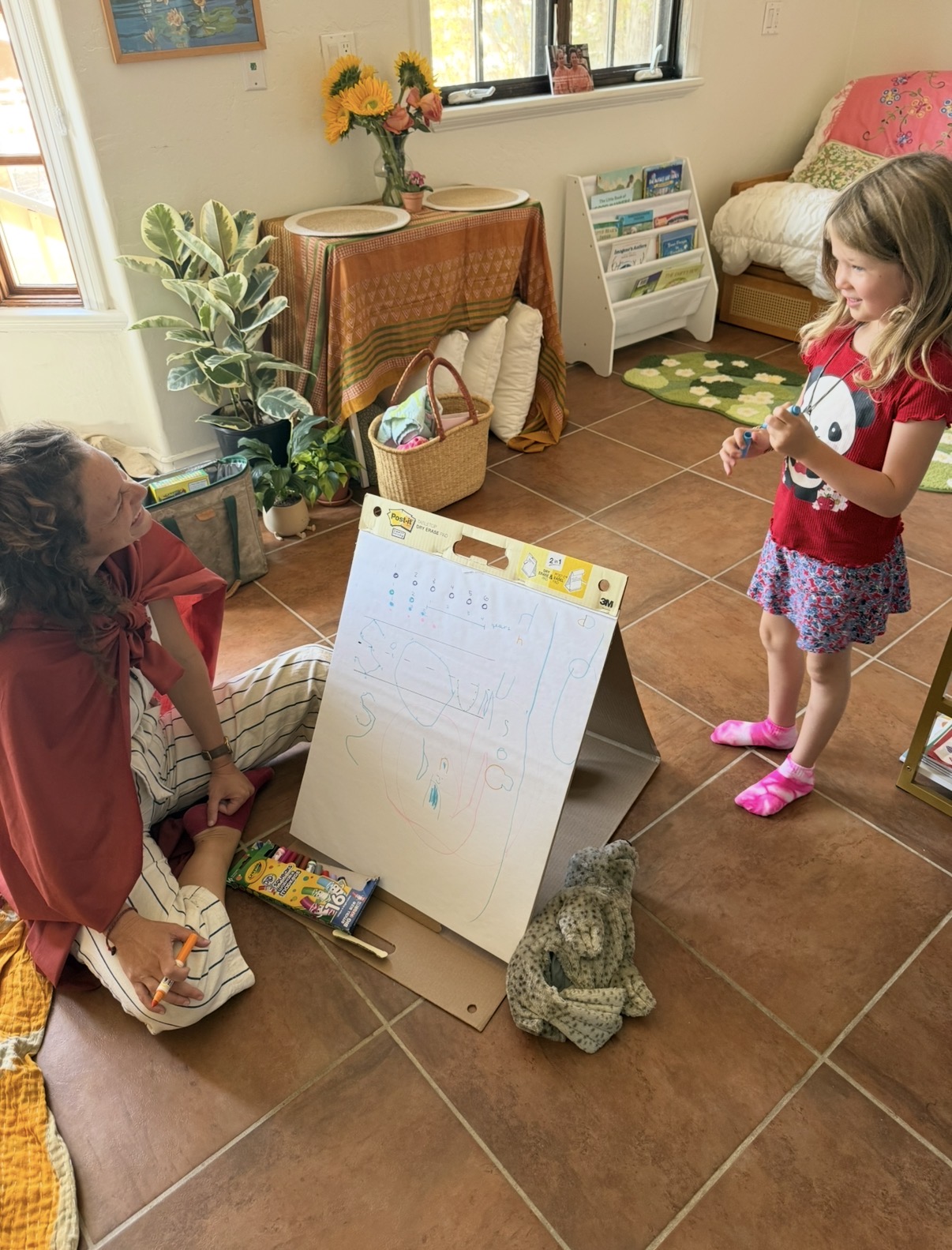A guide seated with a child who is presenting her artwork