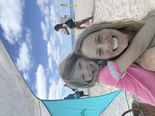 A guide hugging a child on the beach during a weekly field trip